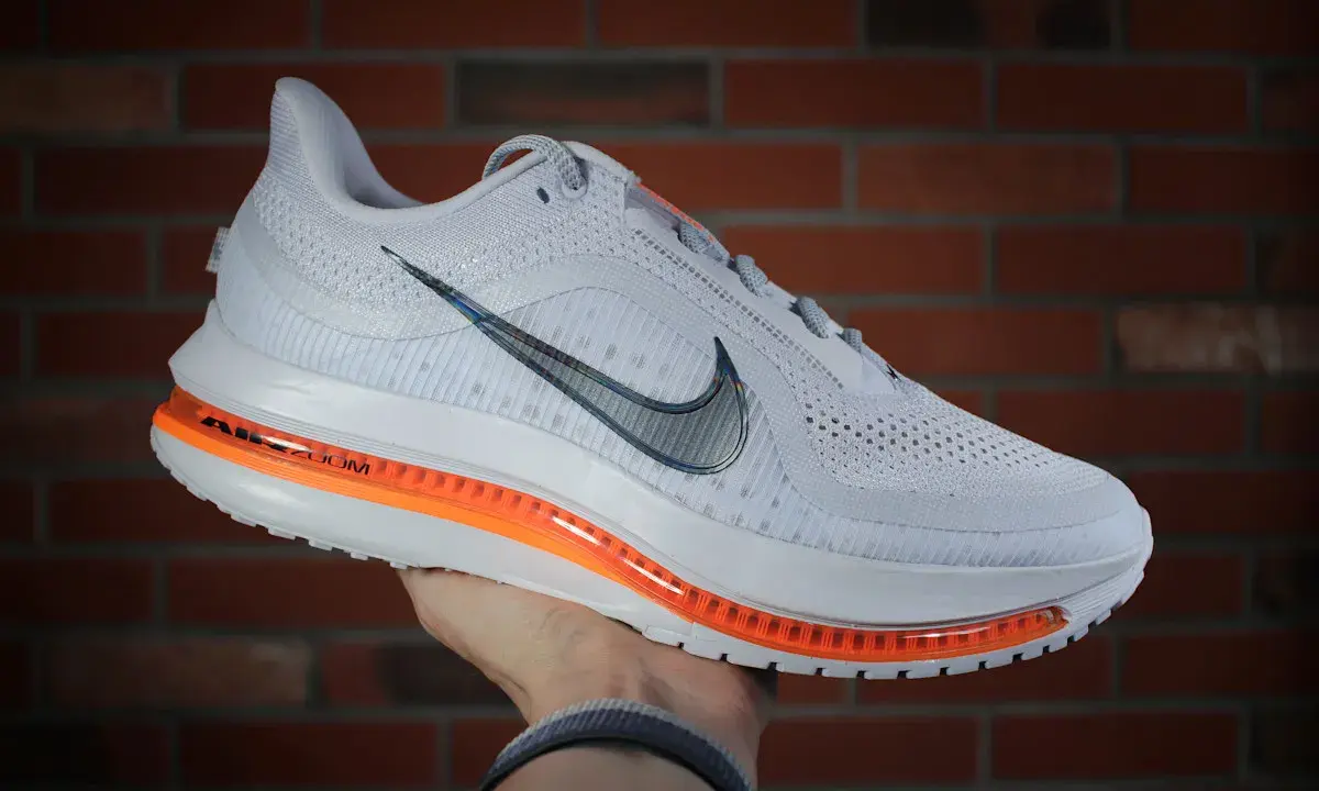 Białe buty sportowe Nike Pegasus Premium z pomarańczową podeszwą Air Zoom, idealne na treningi.