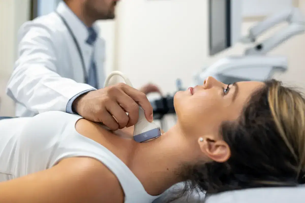 Lekarz wykonuje USG tarczycy u pacjentki, badanie pomocne w diagnostyce chorób takich jak hashimoto objawy.