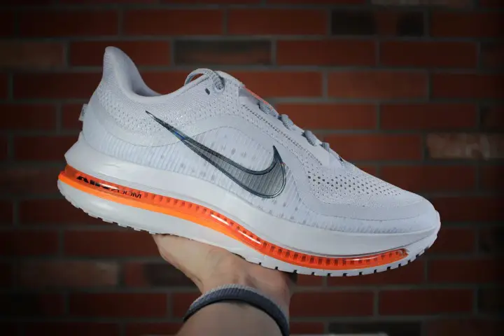 Białe buty sportowe Nike Pegasus Premium z pomarańczową podeszwą Air Zoom, idealne na treningi.