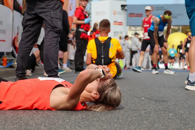 Zmęczona biegaczka leży na ziemi po tym, jak dowiedziała się, ile biegnie się maraton.